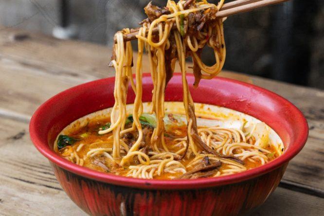Some noodles being held over a bowl of lamb tantanmen at Bone Daddies